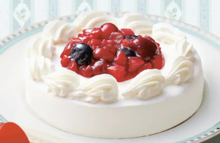 白いクリームと赤いベリーが飾られたホールケーキ